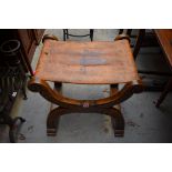 A carved elm and studded tan leather X-frame stool, 56cm wide.