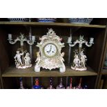 A German porcelain mantel clock, 32.5cm high; together with a similar pair of Sitzendorf figural