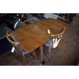 A vintage blonde Ercol drop leaf table and four chairs, 137cm wide.