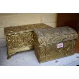 An embossed brass stationary casket, 21.5cm wide; together with another cast brass casket, 27.5cm