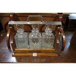 An mahogany and electroplated three bottle tantalus, 40cm wide.
