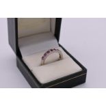 A ruby and diamond half eternity white gold ring, hallmarked 750, 4.2g total weight.