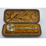 A cased Continental silver plated ornate straining ladle, having gilt bowl, 15cm long,