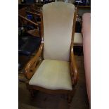 An antique walnut and upholstered open arm rocking chair.