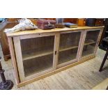 A large antique pine cupboard, with three sliding glass panel doors, 248.5cm wide.