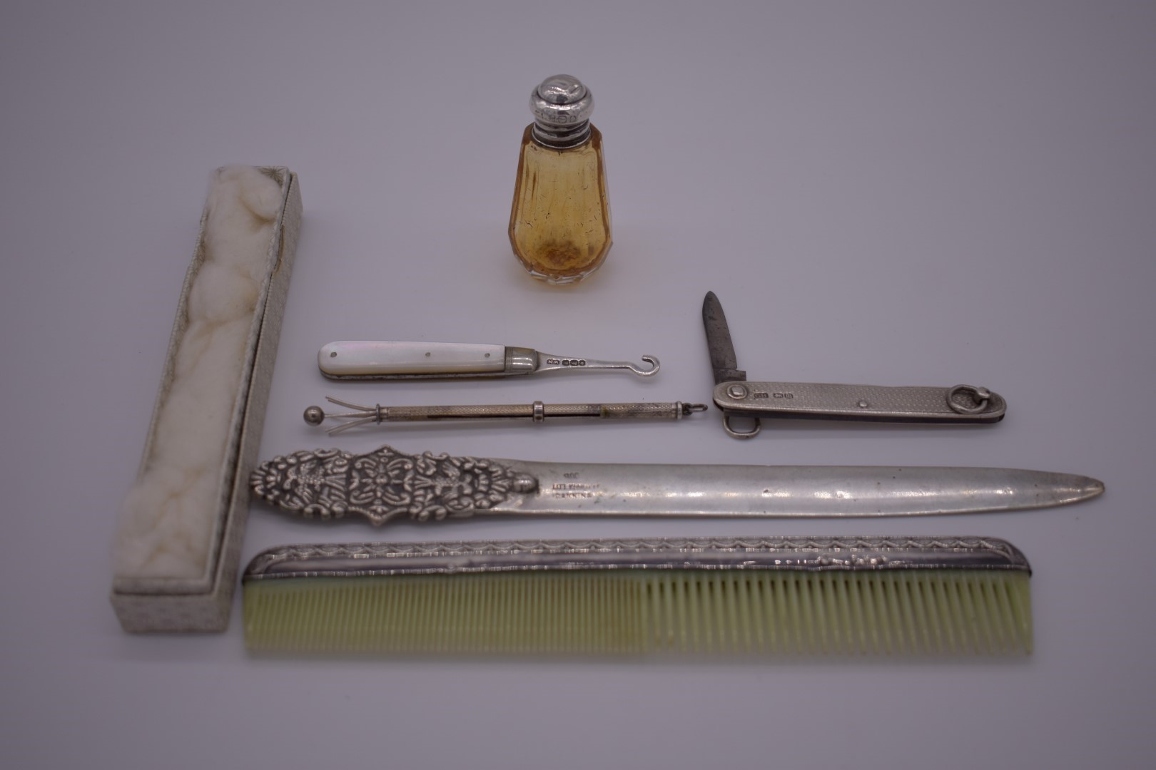 A sterling silver swizzle stick; together with a .800 letter opener; a silver mounted comb; and