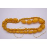 A graduated string of butterscotch amber beads, 66cm approximately, 47.2g.