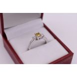 An 18ct white gold diamond three stone ring, set central yellow brilliant cut diamond with a