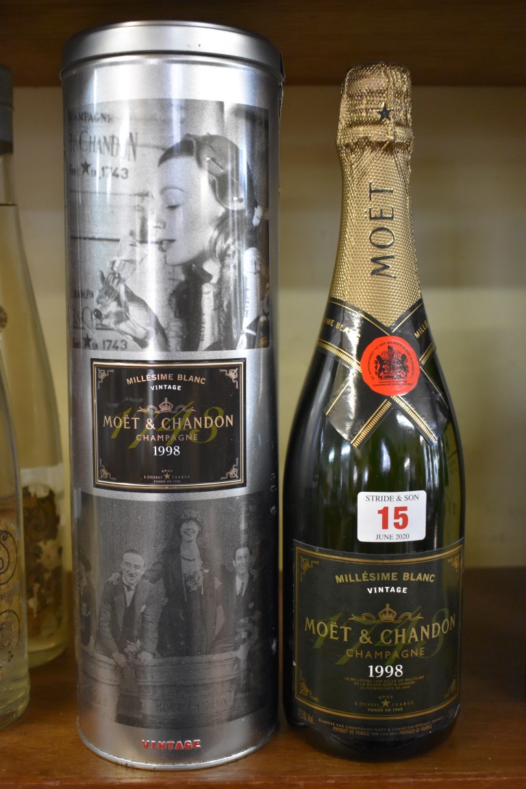 A bottle of Moet 1998 vintage Millesime Blanc champagne, in metal tin.