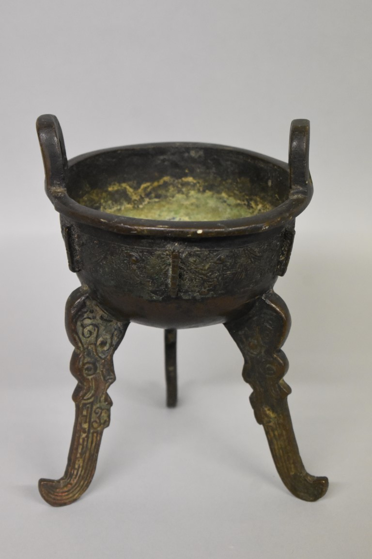 WITHDRAWN FROM SALE A Chinese Archiastic bronze twin handled tripod ding, with stylized decoration.