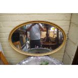 An old green and gilt oval wall mirror, 80cm wide.