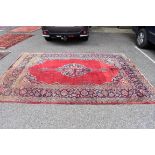 A Persian carpet, having central floral medallion with floral borders on a red ground, 317 x 225cm.