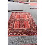 A Persian style rug, having geometric decoration to central field and borders on a red ground, 228 x