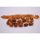 A graduated amber bead necklace, 56cm (including string), 71g; together with another faceted bead