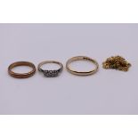 A small group of gold jewellery, comprising: a three stone diamond ring; two wedding bands,