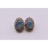 A pair of gold and opal doublet oval ear clips, stamped 575, 17.5mm, 5.8g total weight.