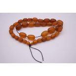 A graduated amber bead necklace, of thirty-seven oval beads, 72g.