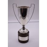 A continental white metal twin handled trophy cup, stamped 800, on wood socle, 31cm total height.