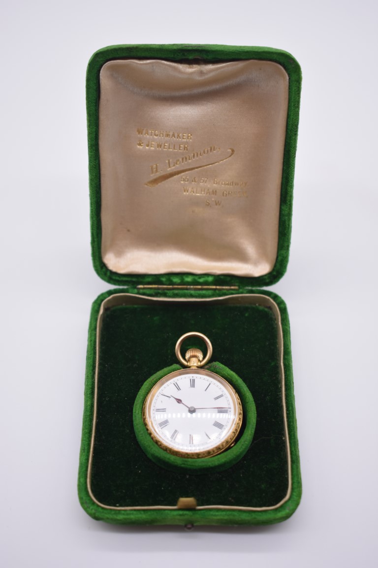 A chased gold stem wind fob watch, stamped 18k, having enamel dial and Roman numerals, 3cm diameter,