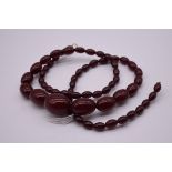 A string of graduated 'cherry amber' beads, 86cm, 62g.