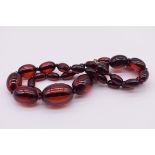 A string of graduated 'cherry amber' beads, 57.5cm, 50.9g.
