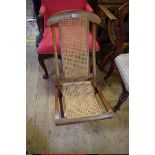 An antique fruitwood and cane folding chair.
