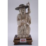 A Japanese carved ivory okimono of a fisherman, signed to base, 18.5cm high, on wood stand.