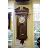 A reproduction oak Vienna style wall clock, striking on gongs, with weights and pendulum.