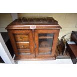 An oak smoker's cabinet, 35cm wide; together with an oak and brass hanging pipe rack; and a