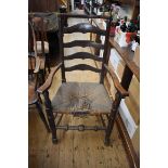 A 19th century fruitwood, beech and ash rush seated ladderback armchair.