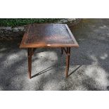 An old oak table having folding legs, the leather top decorated with insects. This lot can only be