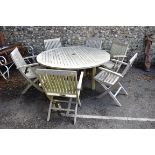 A large circular teak garden table and six matching folding chairs by Barlow Tyrie. This lot can