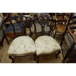 A pair of late Victorian carved mahogany salon chairs, the underside hessian each bearing stencilled