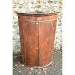 A George III inlaid mahogany barrel fronted corner cupboard, with shelves and drawers to interior.