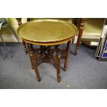 A North African brass top folding table, decorated with Islamic script, 57.5cm diameter.