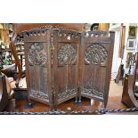 An interesting Arts and Crafts small oak three fold screen, carved in relief with stylized