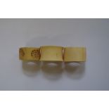 A Chinese carved bone napkin ring; together with two ivory examples.