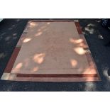 A large modern rug, having geometric borders on a pink ground, 302 x 401cm.