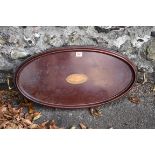 An Edwardian inlaid mahogany oval two handled tray, having inlaid shell decoration to centre, 65cm