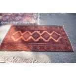 A Bokhara style rug, having five central medallions with floral and geometric borders on a red