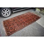 A Bokhara rug, having repeated design to central field, with geometric borders on a red ground,