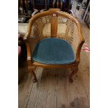 A 1930s walnut and cane tub chair.