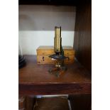 A small lacquered brass field microscope, in box.