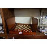 A Victorian mahogany folding chessboard, with bone chess set, the board 30.5cm wide.