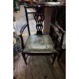 A pair of antique mahogany elbow dining chairs, each with studded green leather seats.