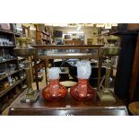 A pair of brass Corinthian column oil lamps, each with 'cranberry' glass shade.