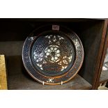 A Damascus carved and shell inlaid plate, inscribed with Islamic script, 27cm diameter, (losses to