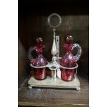 An electroplated two bottle stand, with a pair of associated cranberry glass ewers and stoppers, the