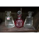 A pair of clear glass decanters and stoppers; together with another cut and cranberry flashed