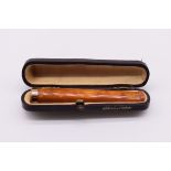 A cased gold mounted amber cheroot holder, stamped 9ct gold, 8cm long, 6.9g gross weight.